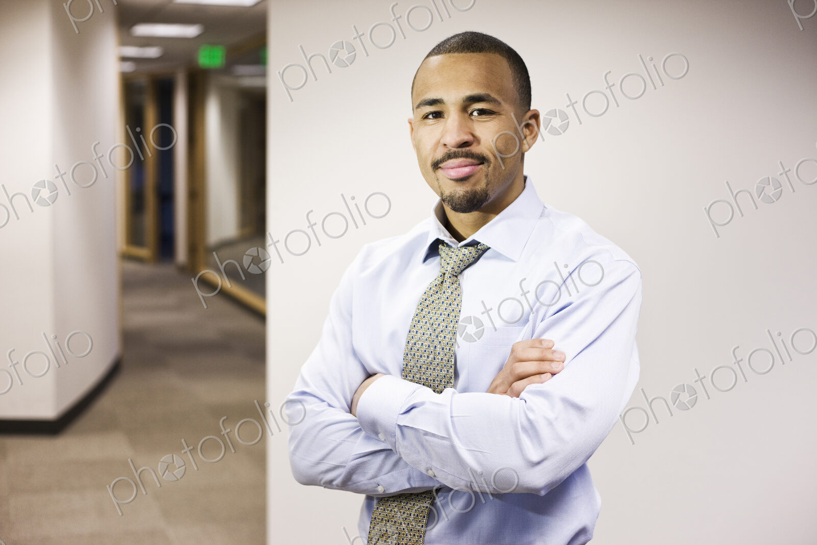 A portrait of a black businessman standing alone in his office space.