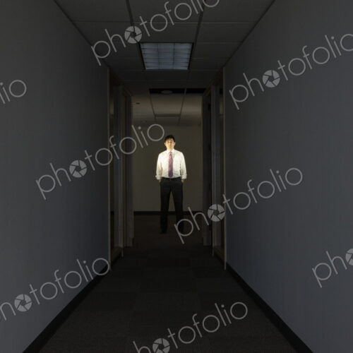 A portrait of a black businessman standing at the end of a long dark hallway. A portrait of a black businessman standing at the end of a long dark hallway.