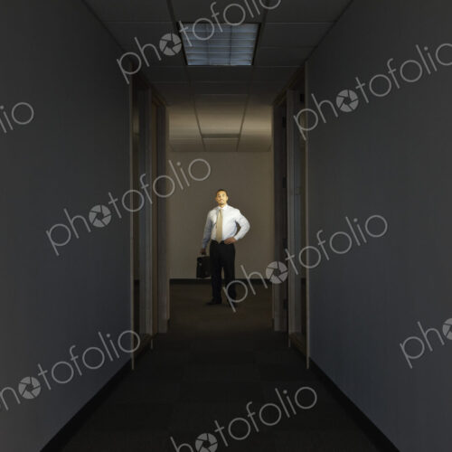 A portrait of a black businessman standing at the end of a long dark hallway. A portrait of a black businessman standing at the end of a long dark hallway.