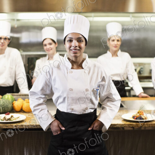A portrait of a black female chef and her team of chefs in the backgroiund of a… A portrait of a black female chef and her team of chefs in the backgroiund of a…