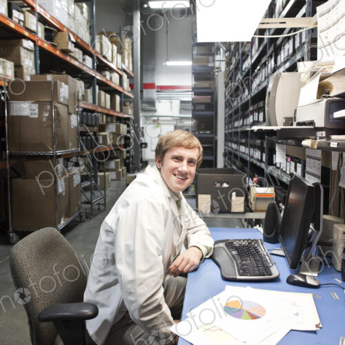 A portrait of a caucaisan male technician sitting at his desk in a parts department in…