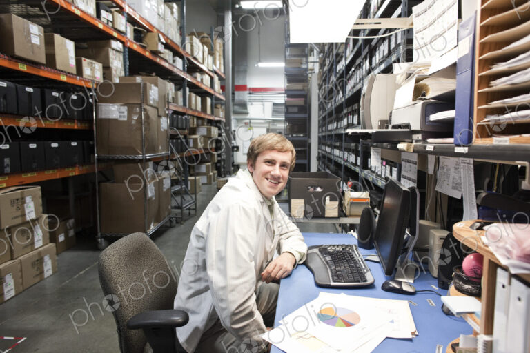 A portrait of a caucaisan male technician sitting at his desk in a parts department in…