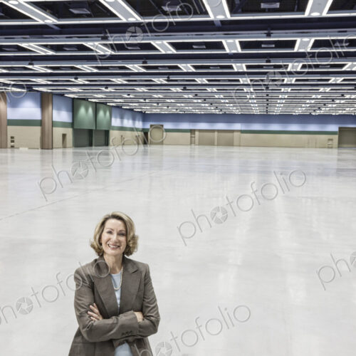 A portrait of a caucasian businesswoman in a convention center arena area.