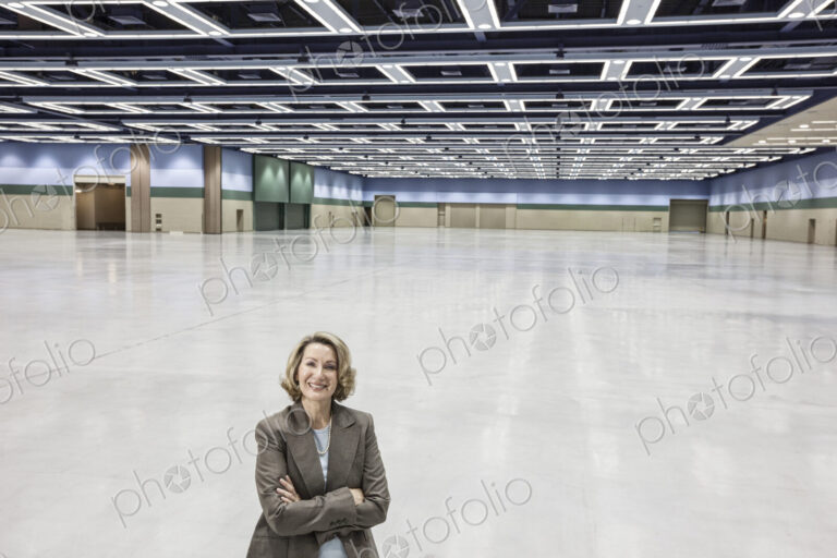 A portrait of a caucasian businesswoman in a convention center arena area.