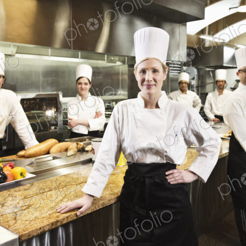 A portrait of a caucasian female chef and her team of chefs in the backgroiund. A portrait of a caucasian female chef and her team of chefs in the backgroiund.