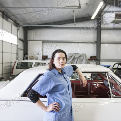 A portrait of a caucasian female mechanic in a car repair shop.