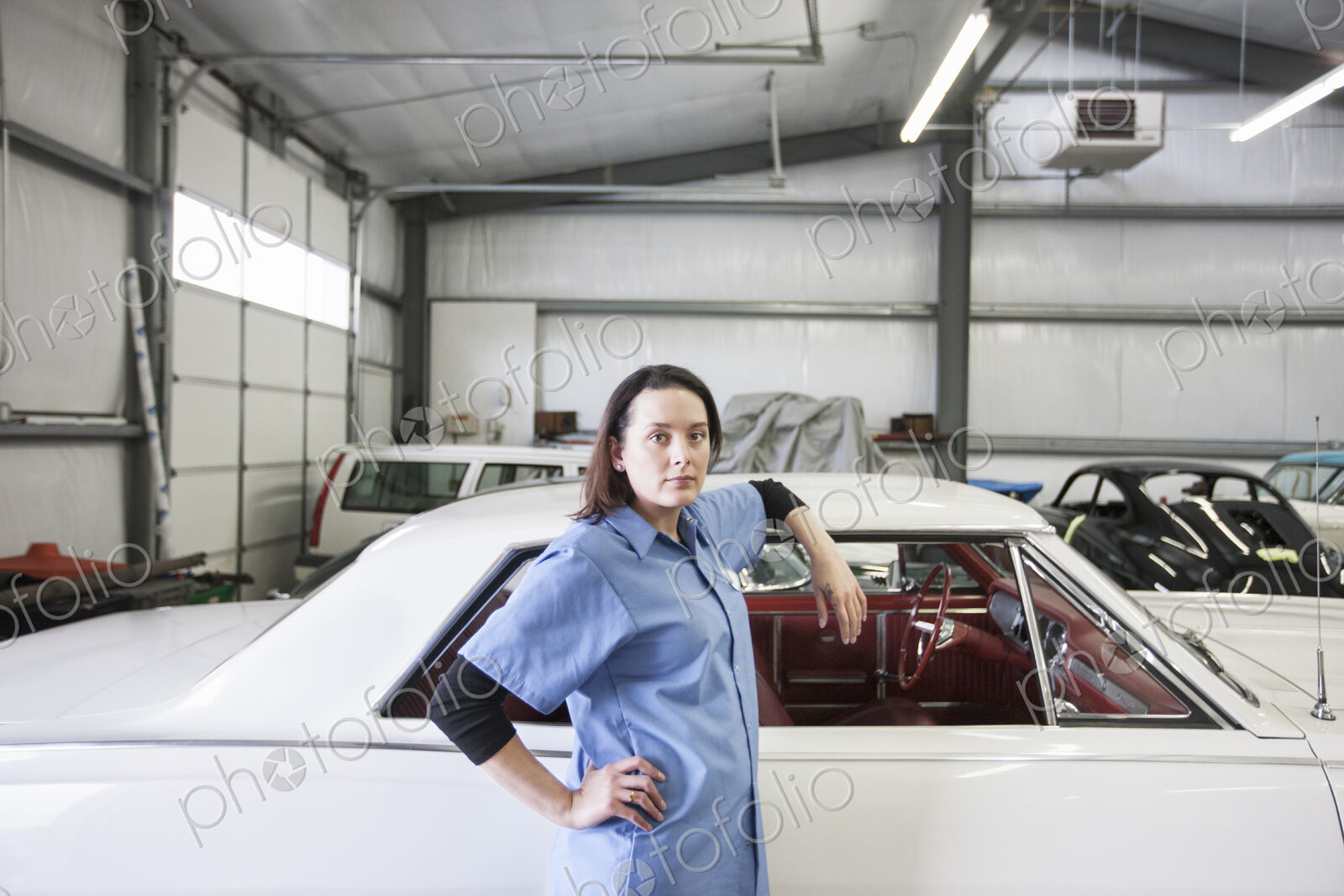 A portrait of a caucasian female mechanic in a car repair shop.