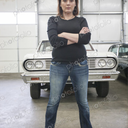 A portrait of a caucasian female mechanic in a car repair shop.