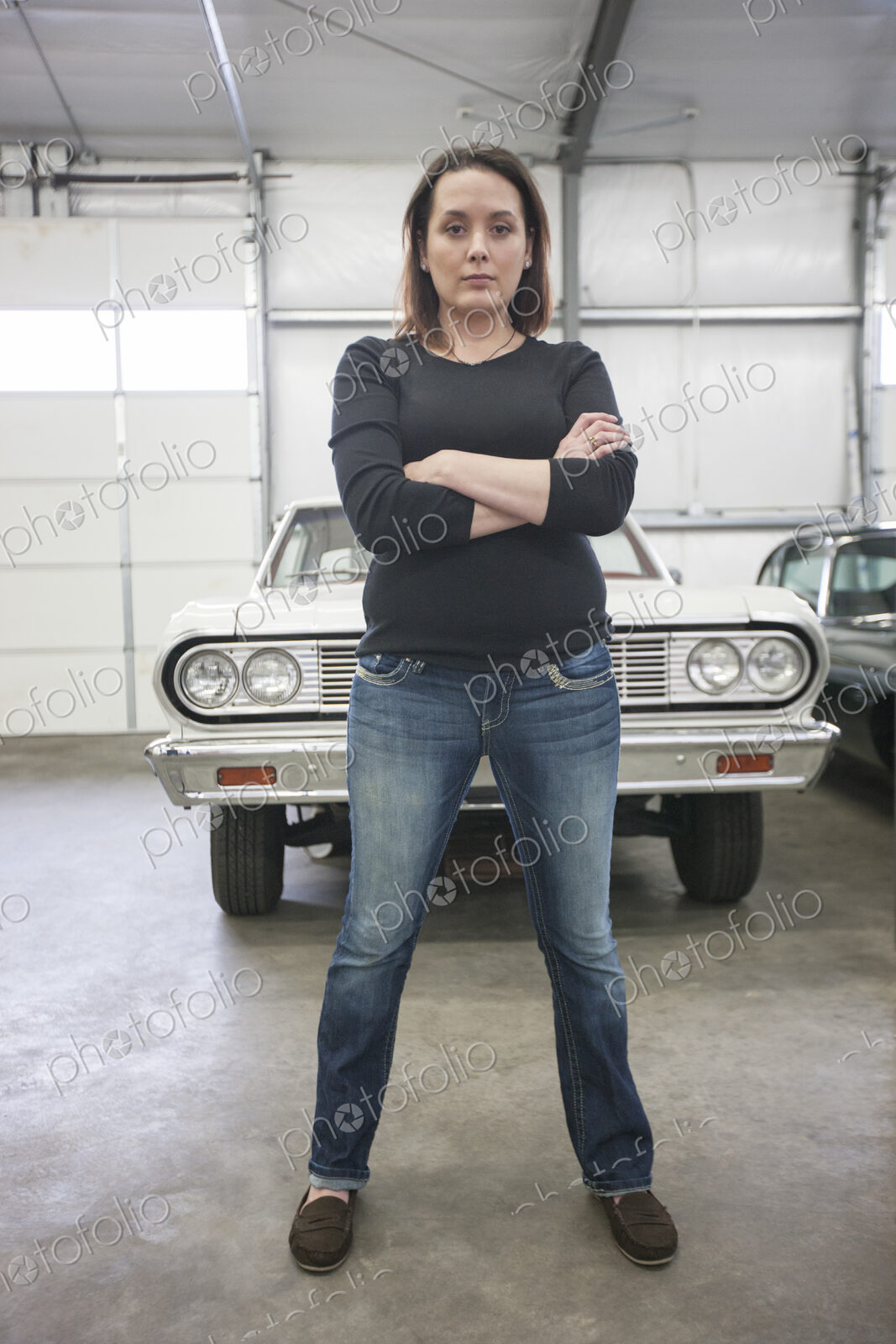 A portrait of a caucasian female mechanic in a car repair shop.