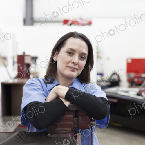 A portrait of a caucasian female mechanic in a car repair shop.
