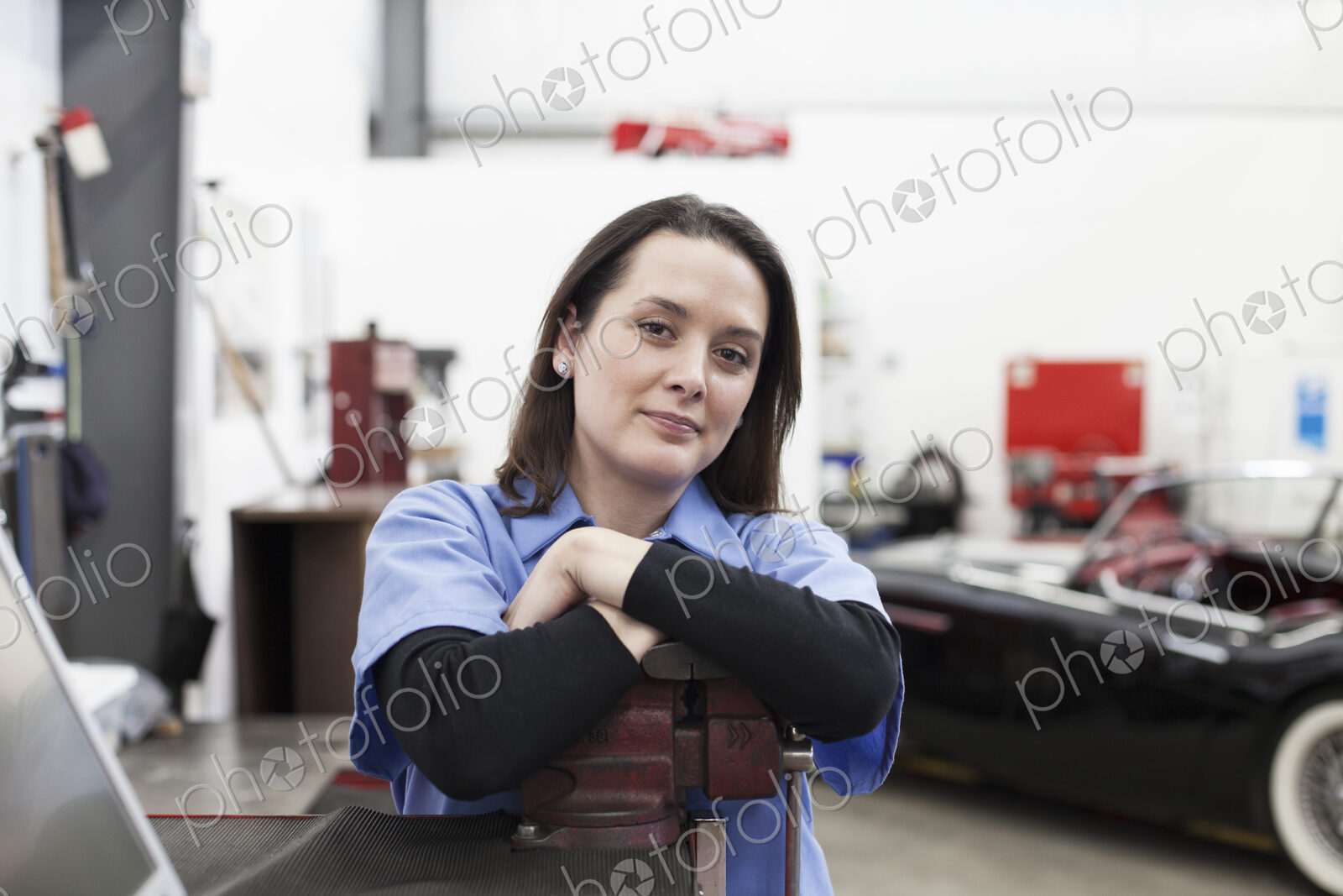 A portrait of a caucasian female mechanic in a car repair shop.