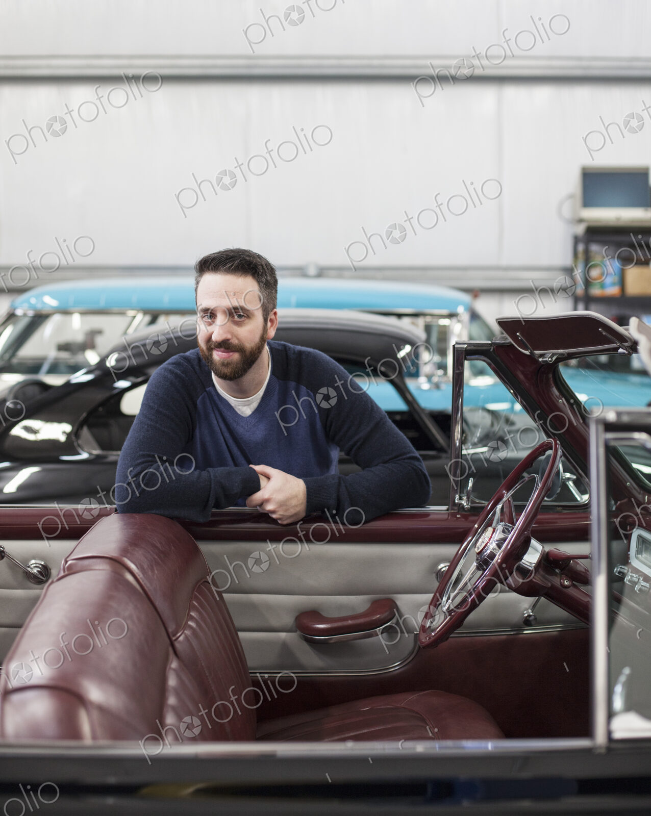 A portrait of a caucasian male leaving on the side of his classic car convertible in a…