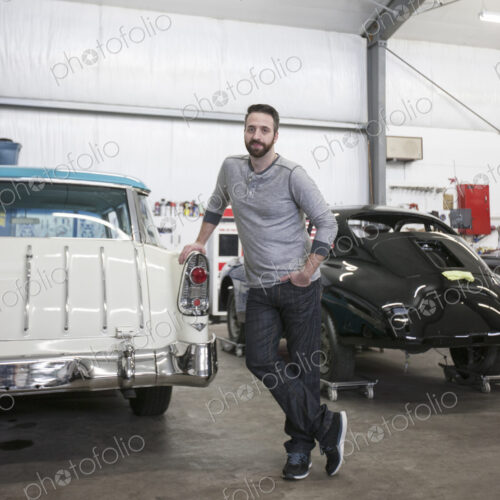 A portrait of a caucasian mechanic in his classic car repair shop.