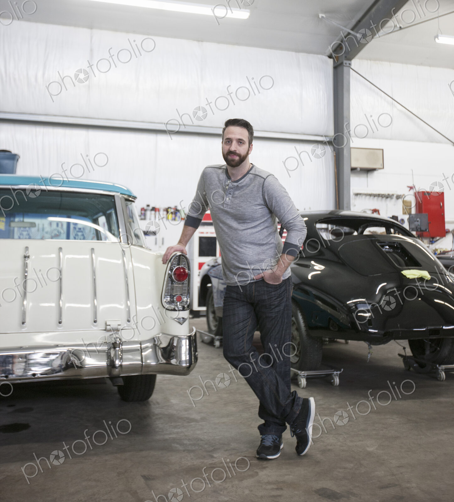 A portrait of a caucasian mechanic in his classic car repair shop.