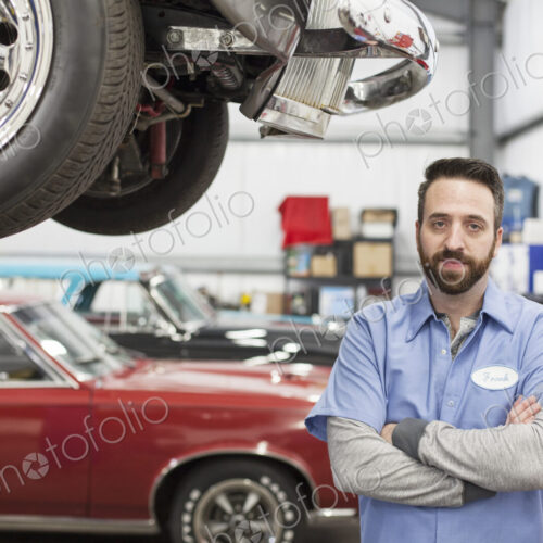 A portrait of a caucasian mechanic in his classic car repair shop.