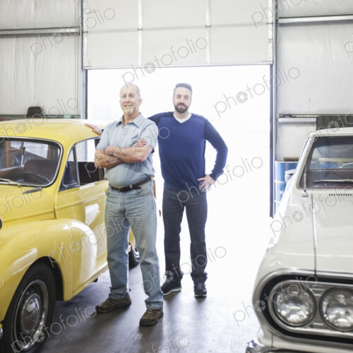 A portrait of a caucasian senior car mechanic and his son in their classic car repair… A portrait of a caucasian senior car mechanic and his son in their classic car repair…