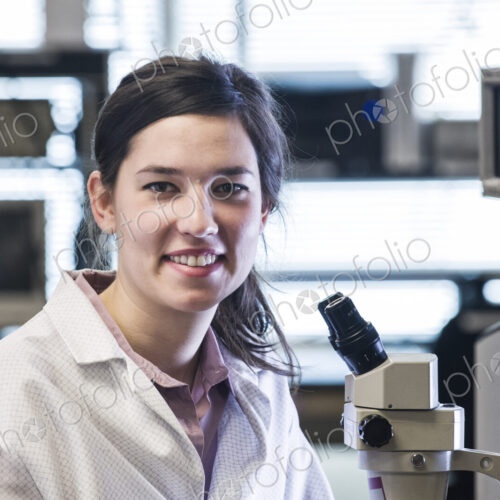 A portrait of a female techniciain at a microscope in a technical research and…