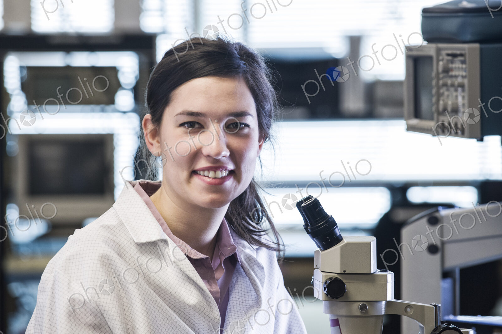 A portrait of a female techniciain at a microscope in a technical research and…