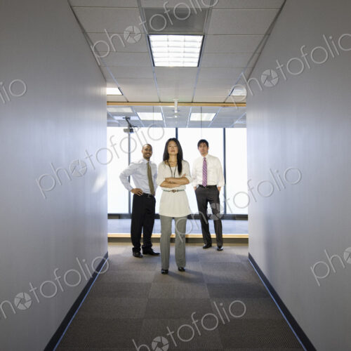 A portrait of a mixed group of business people standing at the end of a long hallway. A portrait of a mixed group of business people standing at the end of a long hallway.