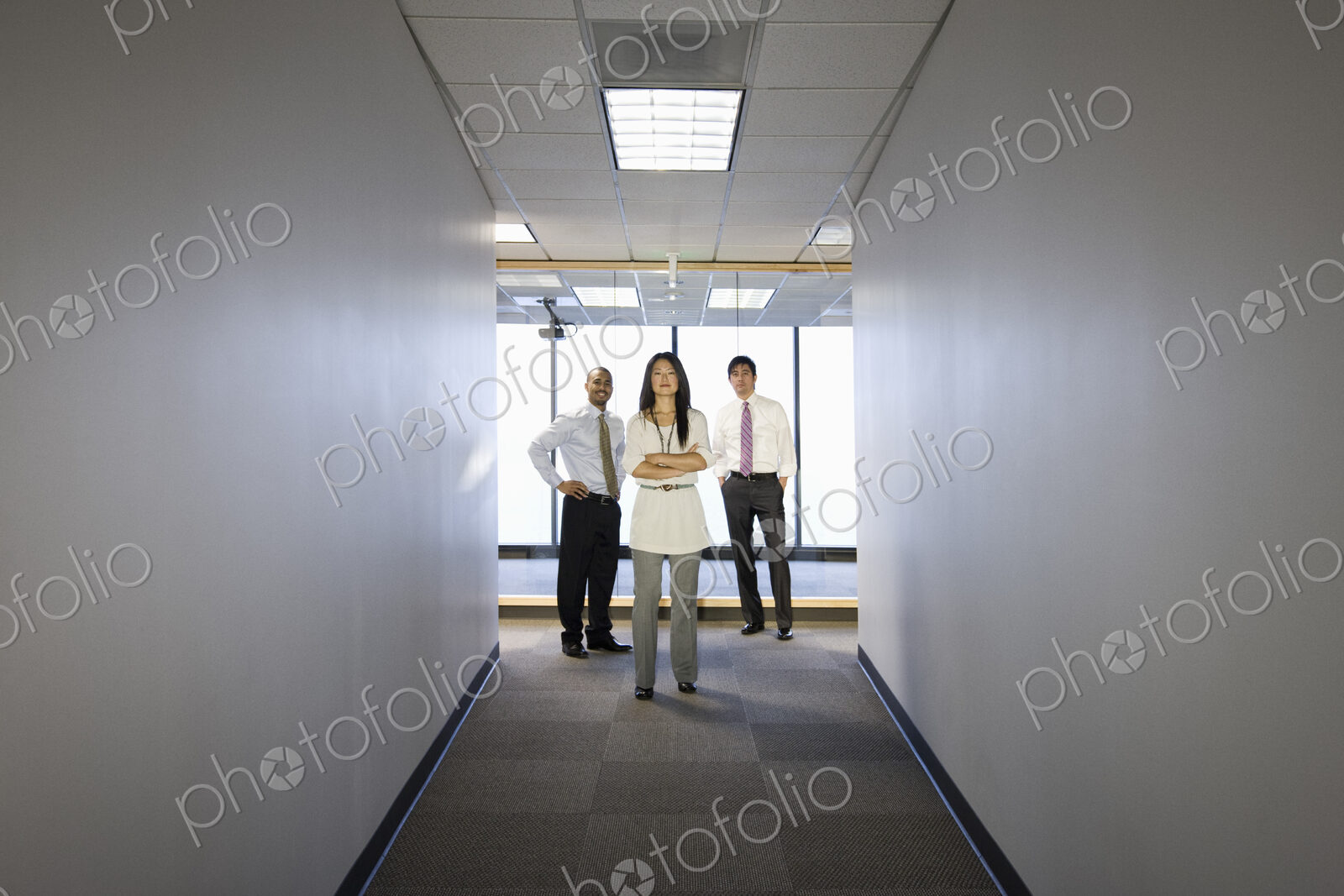 A portrait of a mixed group of business people standing at the end of a long hallway.