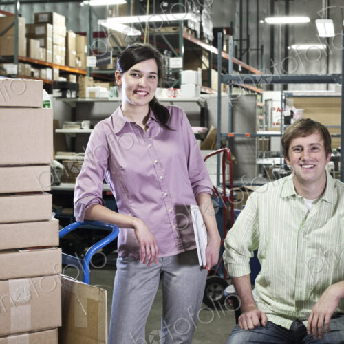 A portrait of a team of two caucasian male and female workers in a parts department…