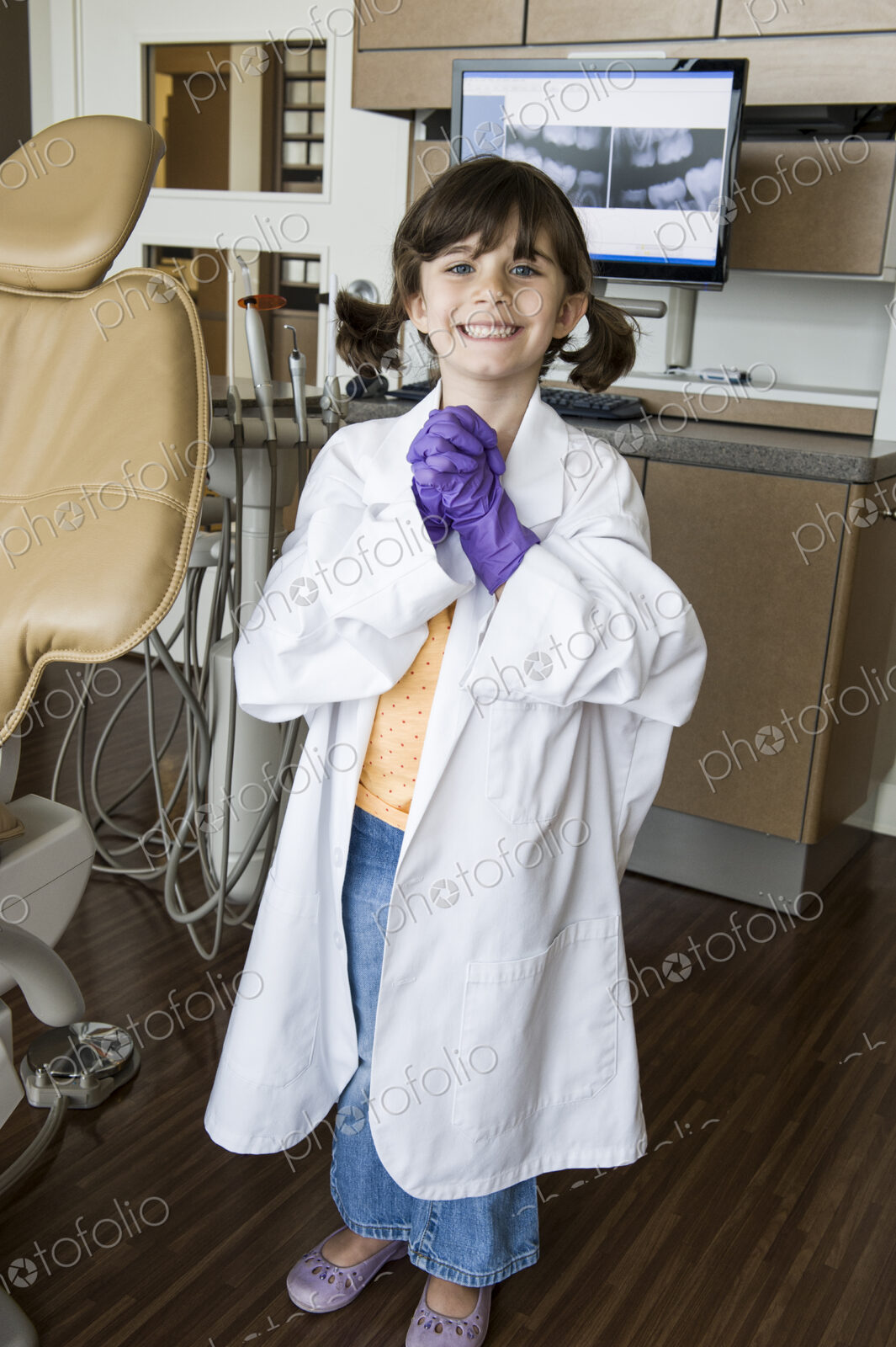 A portrait of a young Caucasian girl playing dress up in a dental office.