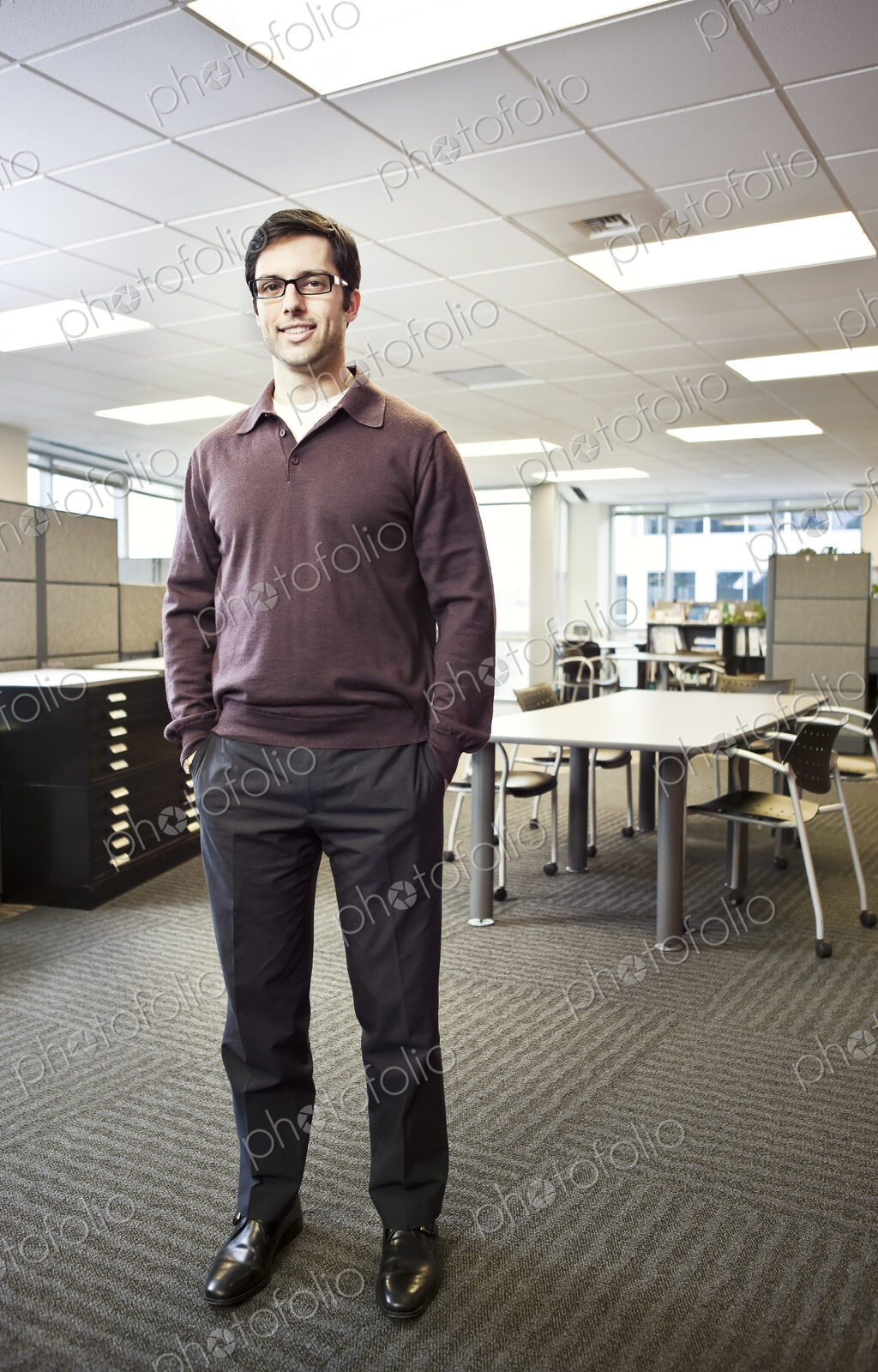 A portrait of a young Hispanic businessman standing in his office.