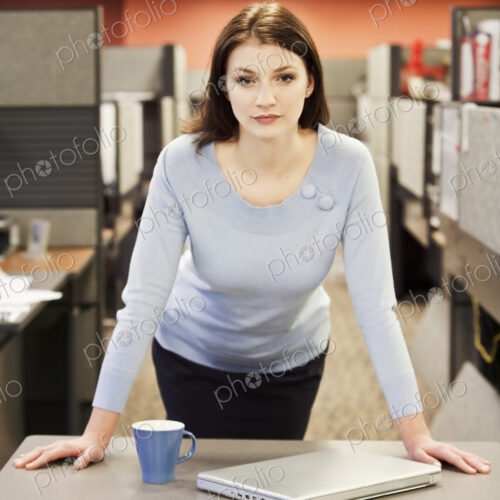 A portrait of a young business woman in her cubicle in a corporate office. A portrait of a young business woman in her cubicle in a corporate office.