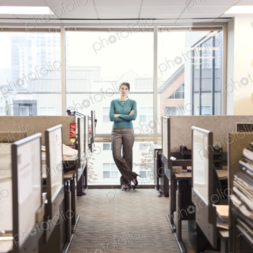 A portrait of a young businesswoman standing at a window near cubicles in a corporate… A portrait of a young businesswoman standing at a window near cubicles in a corporate…