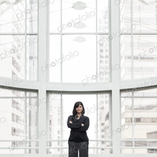 A portrait of a young businesswoman standing by a window in a lobby. A portrait of a young businesswoman standing by a window in a lobby.