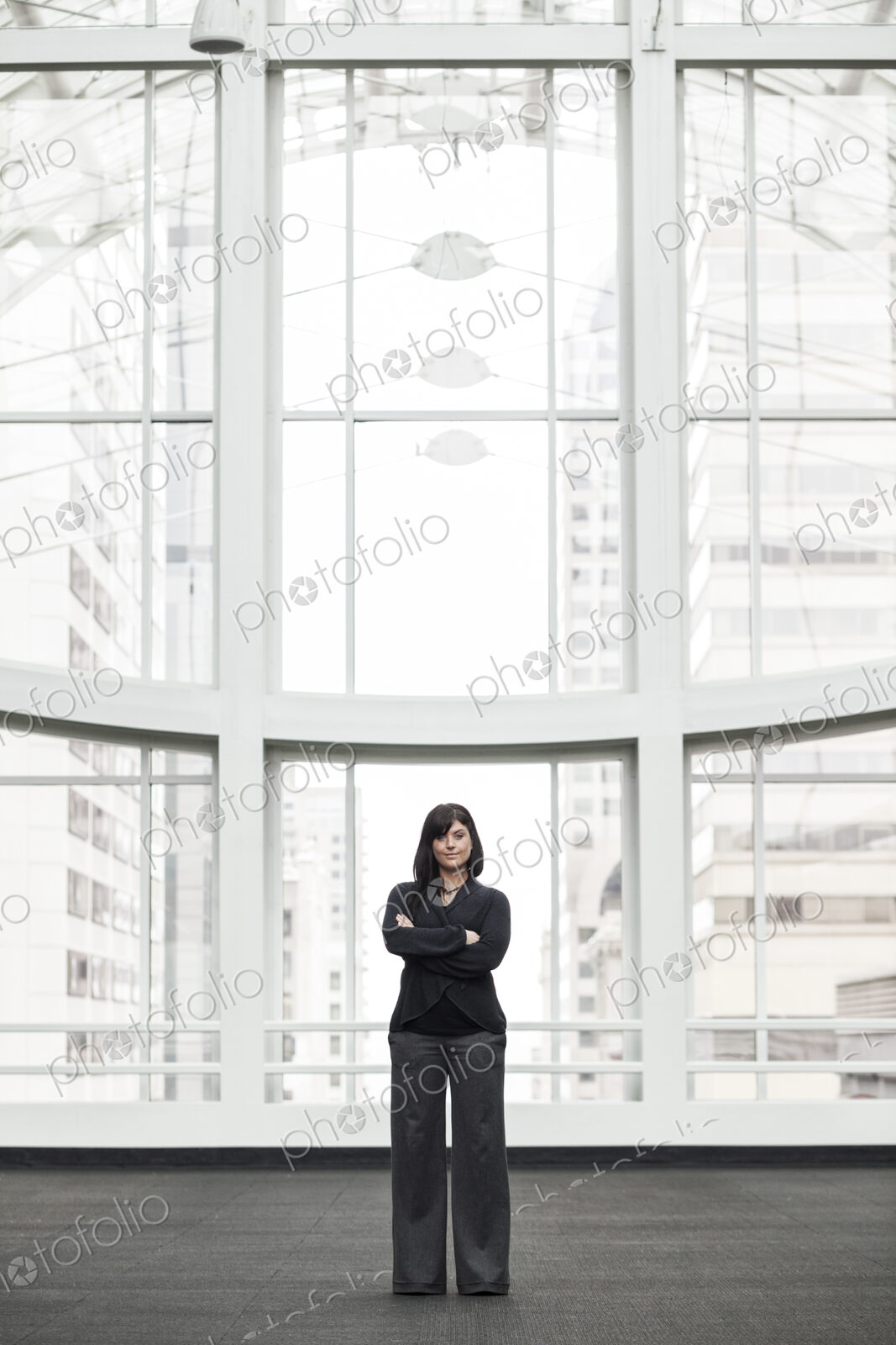 A portrait of a young businesswoman standing by a window in a lobby.