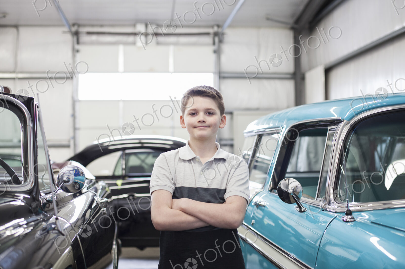 A portrait of a young caucasian boy in his father’s classic car repair shop.
