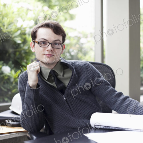 A portrait of a young hip businessman sitting in his office. A portrait of a young hip businessman sitting in his office.