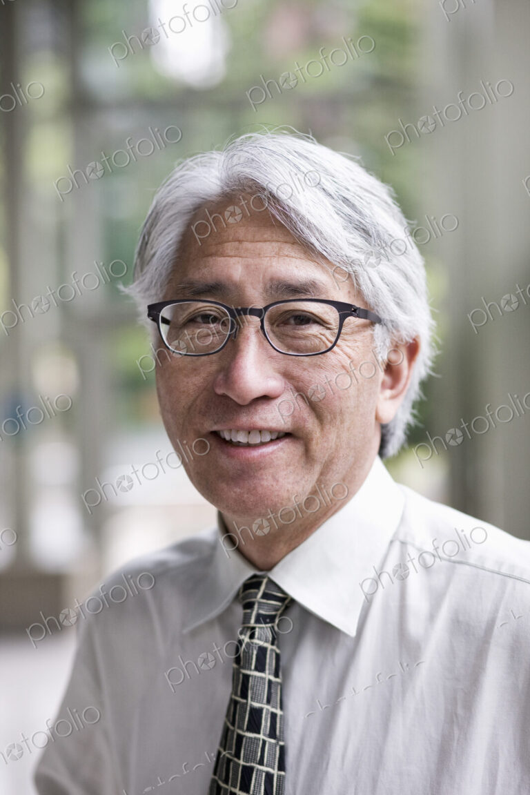 A portrait of an Asian businessman in a convention center setting.
