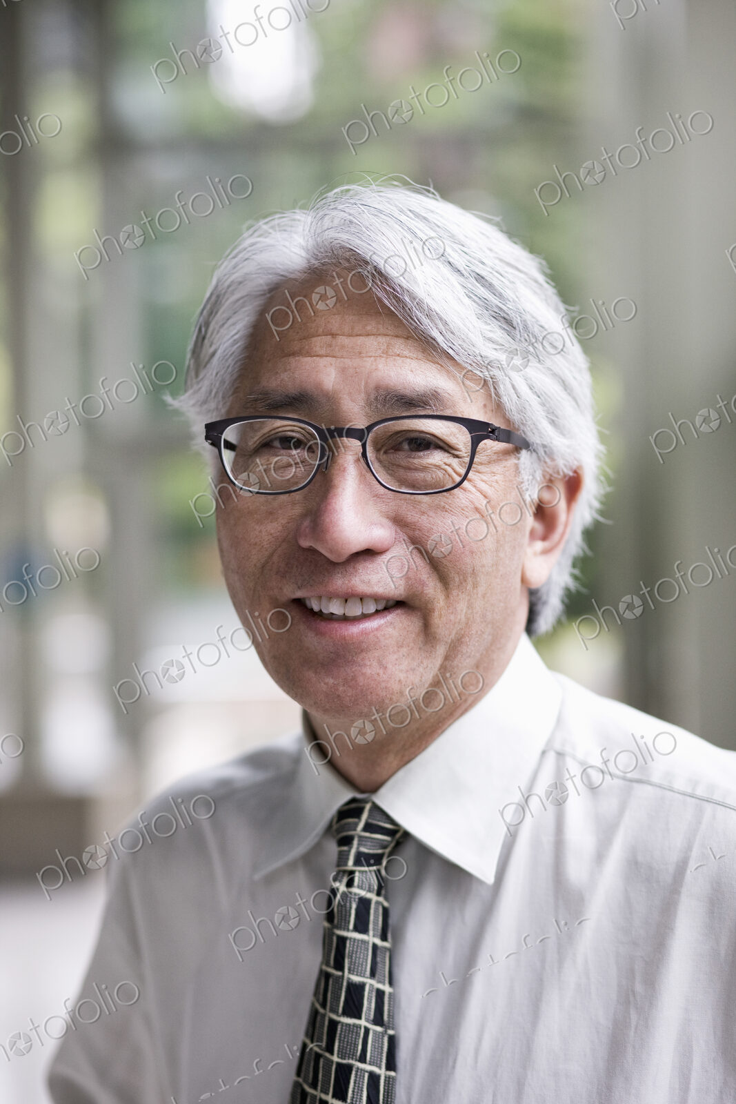 A portrait of an Asian businessman in a convention center setting.