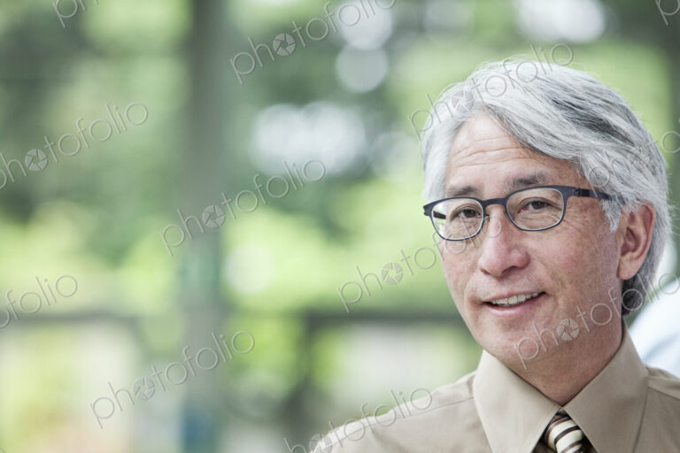 A portrait of an Asian businessman in a convention center setting.