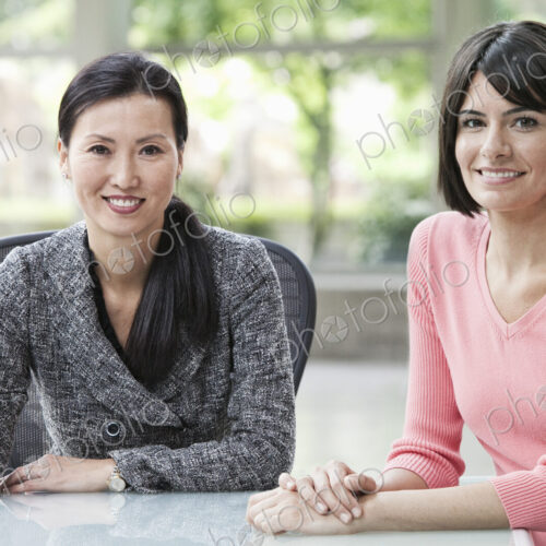 A portrait of an Asian businesswoman and a Hispanic business woman in an office. A portrait of an Asian businesswoman and a Hispanic business woman in an office.
