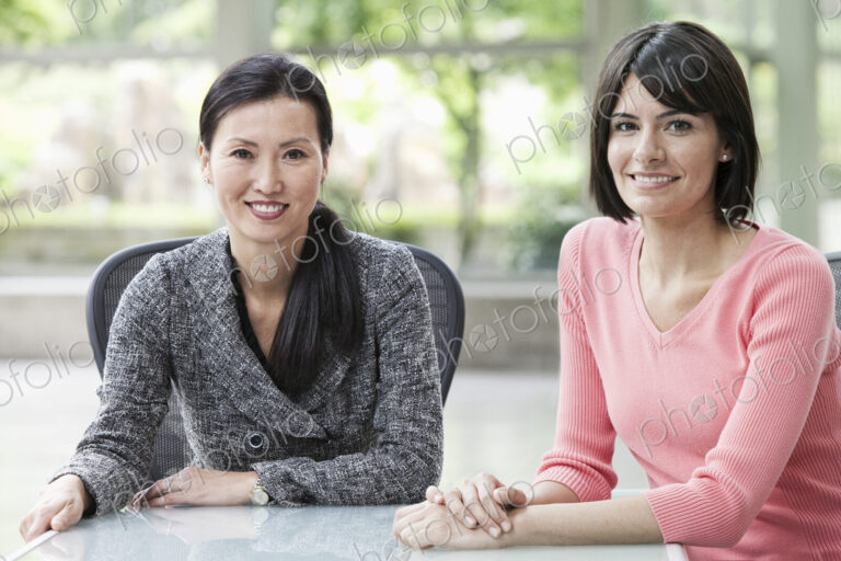 A portrait of an Asian businesswoman and a Hispanic business woman in an office.