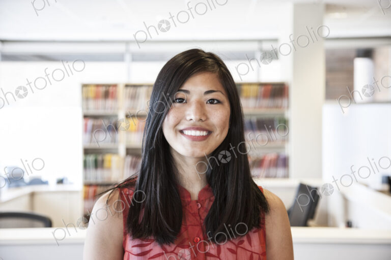 A portrait of an Asian businesswoman in her office looking at the camera.