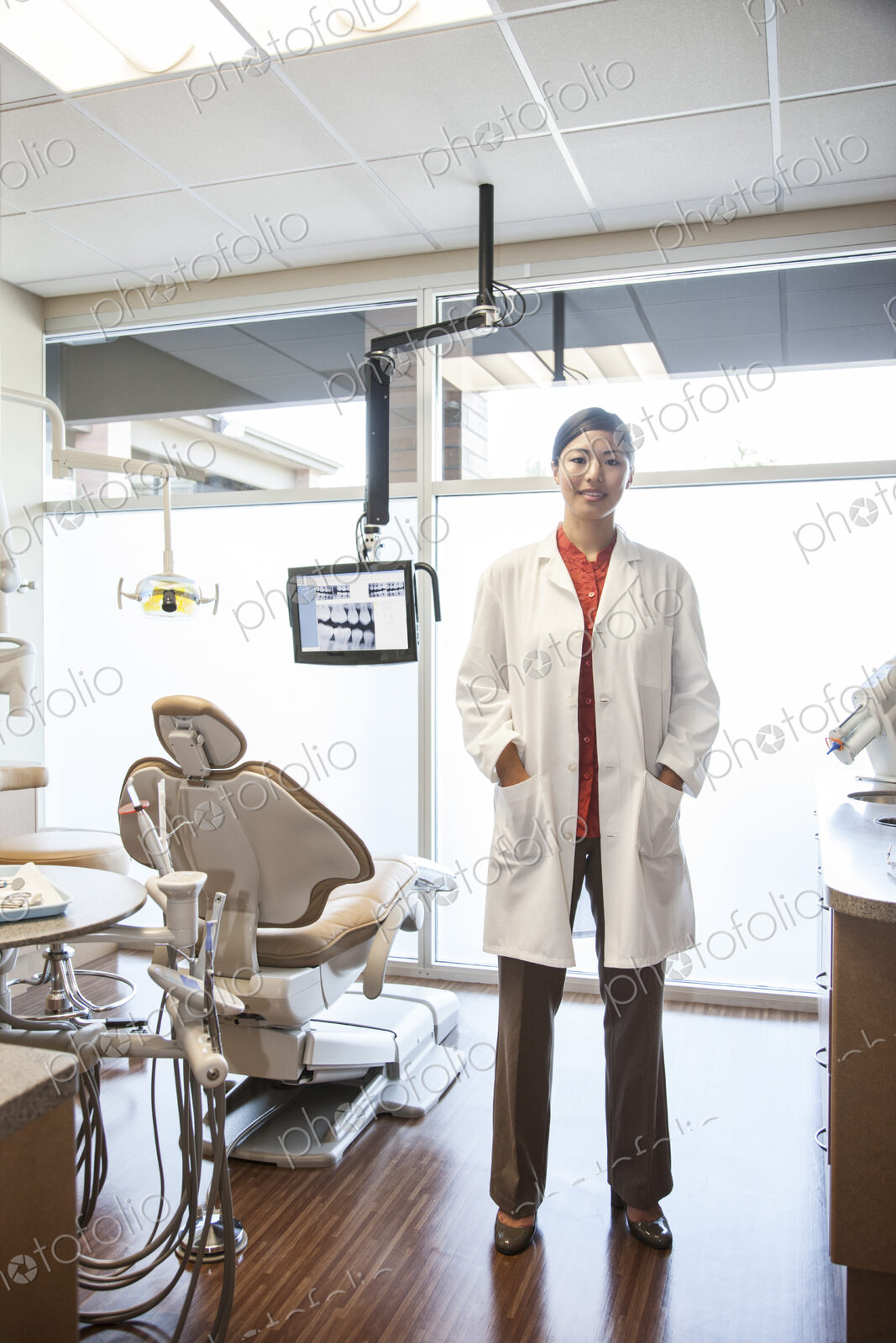 A portrait of an Asian female dentist in her office.