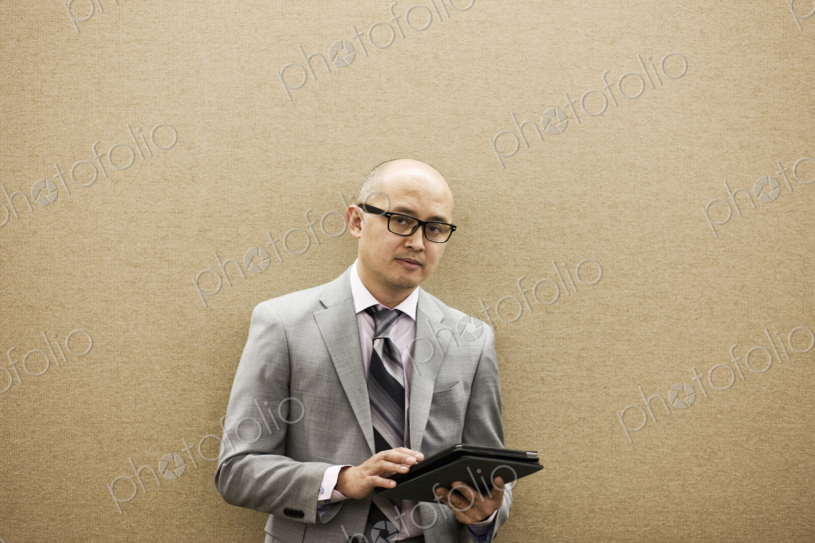 A portrait of an asian businessman holding a notebook computer.