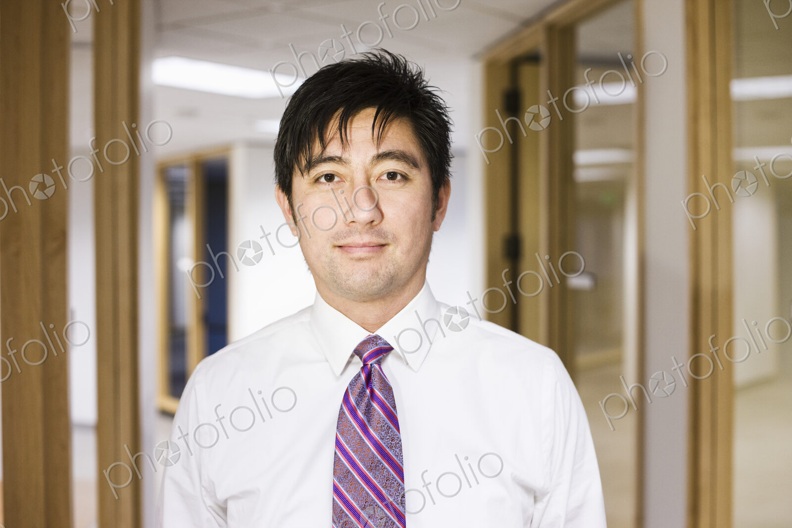 A portrait of an asian businessman standing alone in his office space.