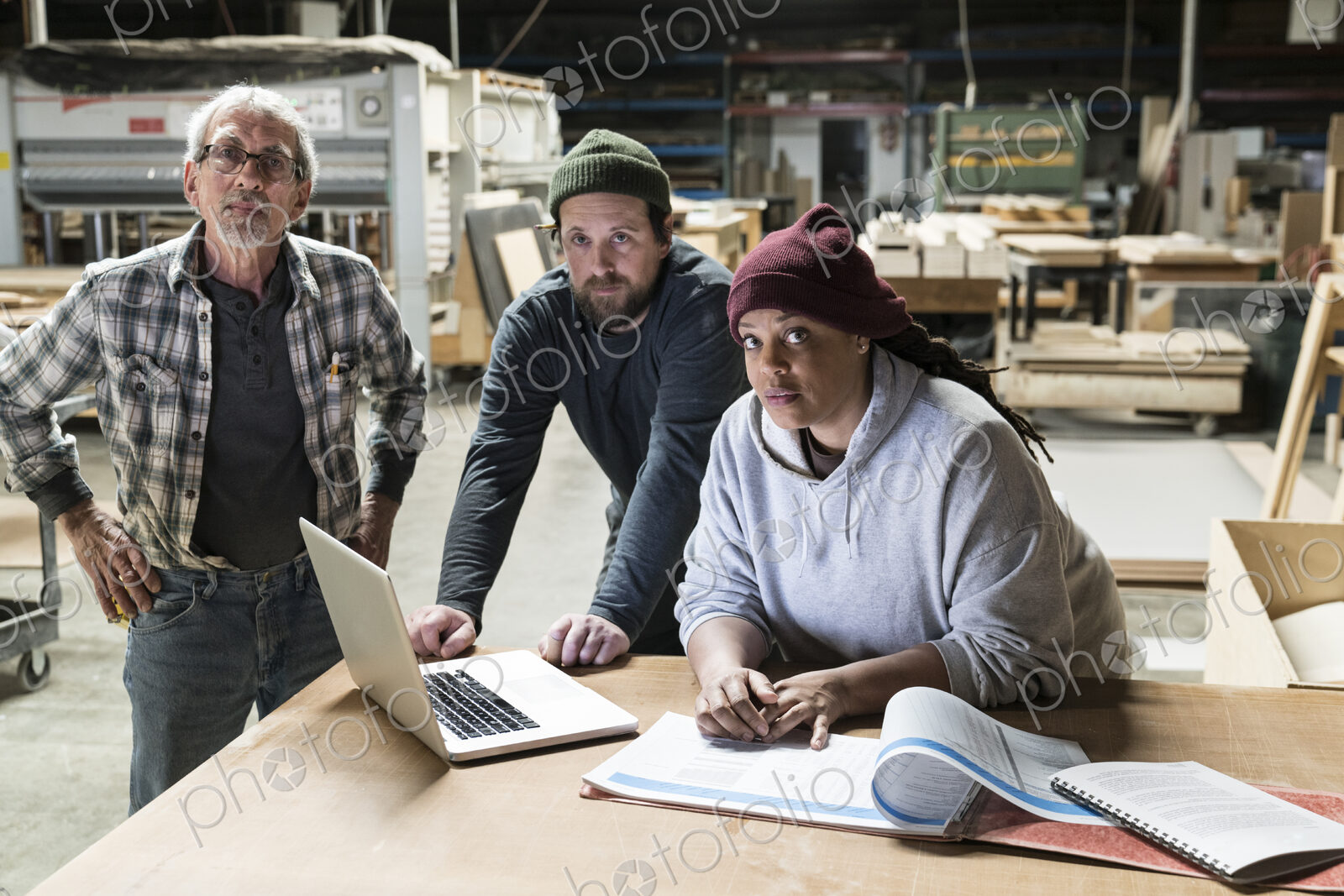 A portrati of mixed race carpenters around a laptop computer after work hours in a…