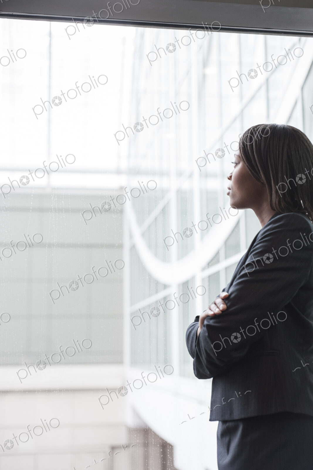 A portriat of a black businesswoman standing at a window in a convention center lobby.