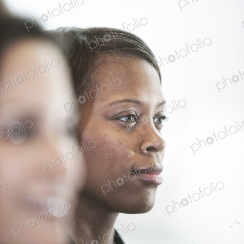 A portriat of a black businesswoman standing at a window in a convention center lobby. A portriat of a black businesswoman standing at a window in a convention center lobby.