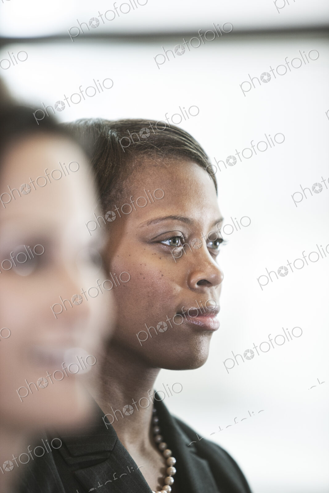 A portriat of a black businesswoman standing at a window in a convention center lobby.