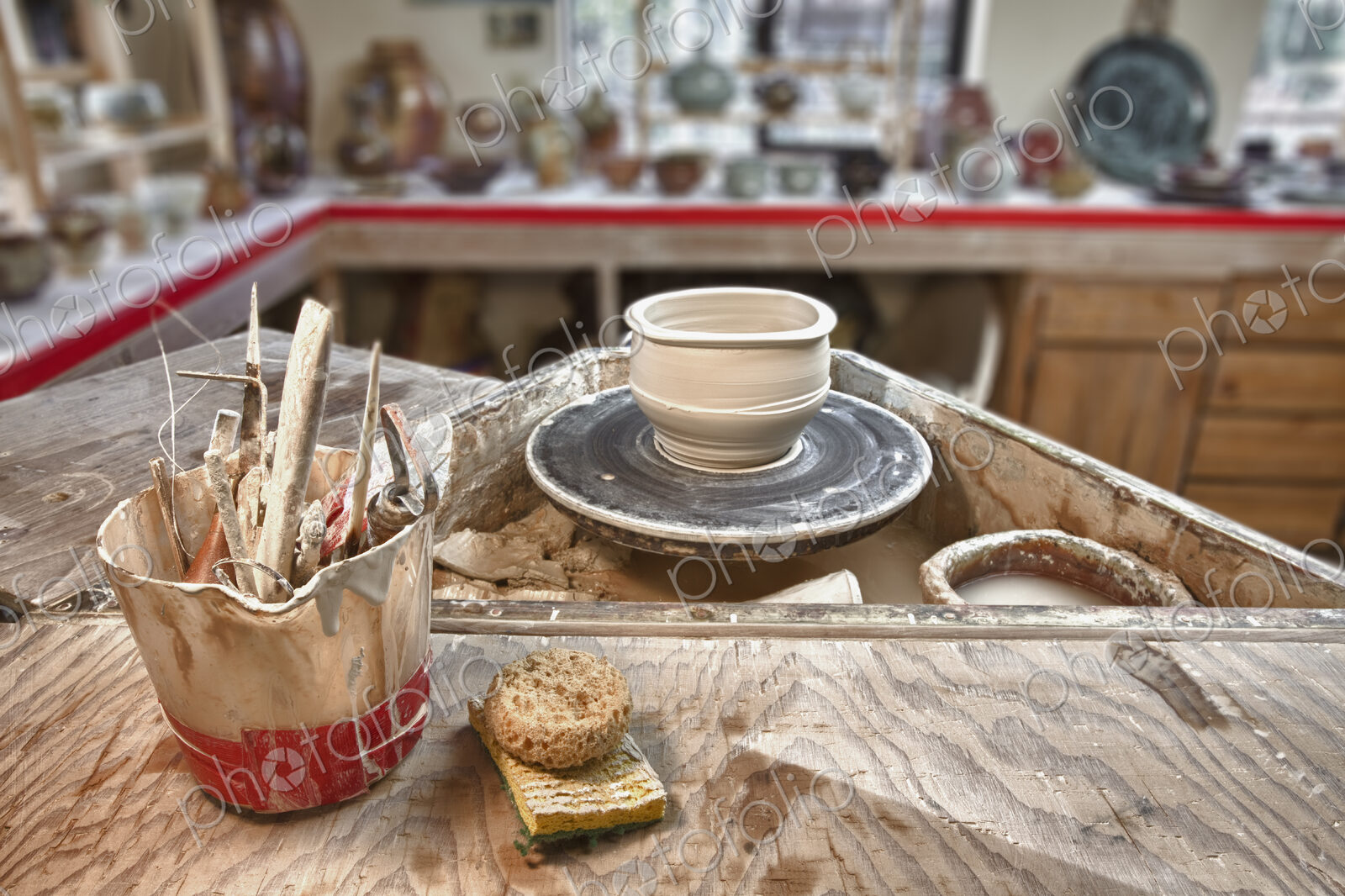 A potter’s workshop, a potters wheel, working tools and sponges on a board, displays…