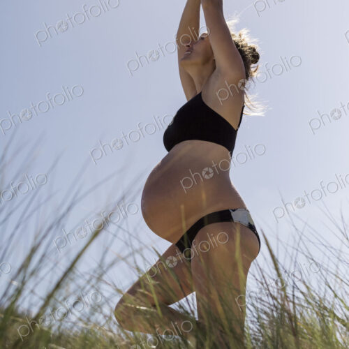 A pregnant woman standing in a yoga pose in the sunshine. A pregnant woman standing in a yoga pose in the sunshine.