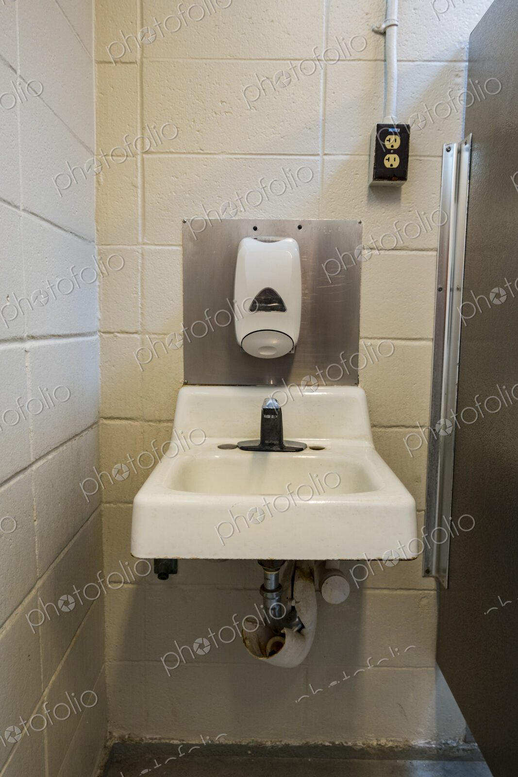 A public restroom toilet at a reststop on a major road, a washbasin for handwashing.