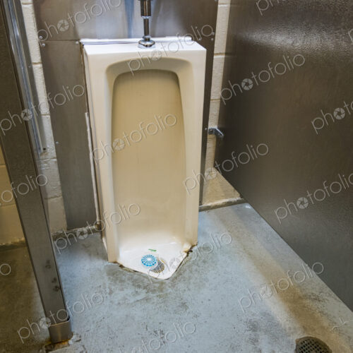 A public restroom urinal, a toilet at a reststop on a major road. A public restroom urinal, a toilet at a reststop on a major road.